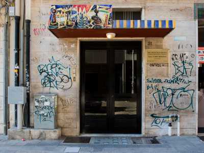 Siamo ora in piazza Aldo Moro 31, dove raggiungiamo un portone arricchito da una lastra in ceramica a firma sempre di Belardinelli